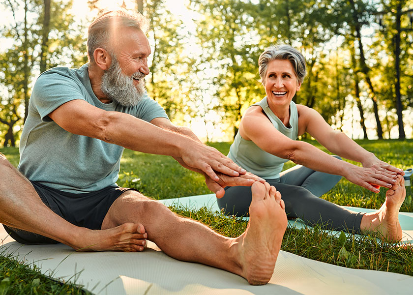 Retired couple stretching on mats outdoors